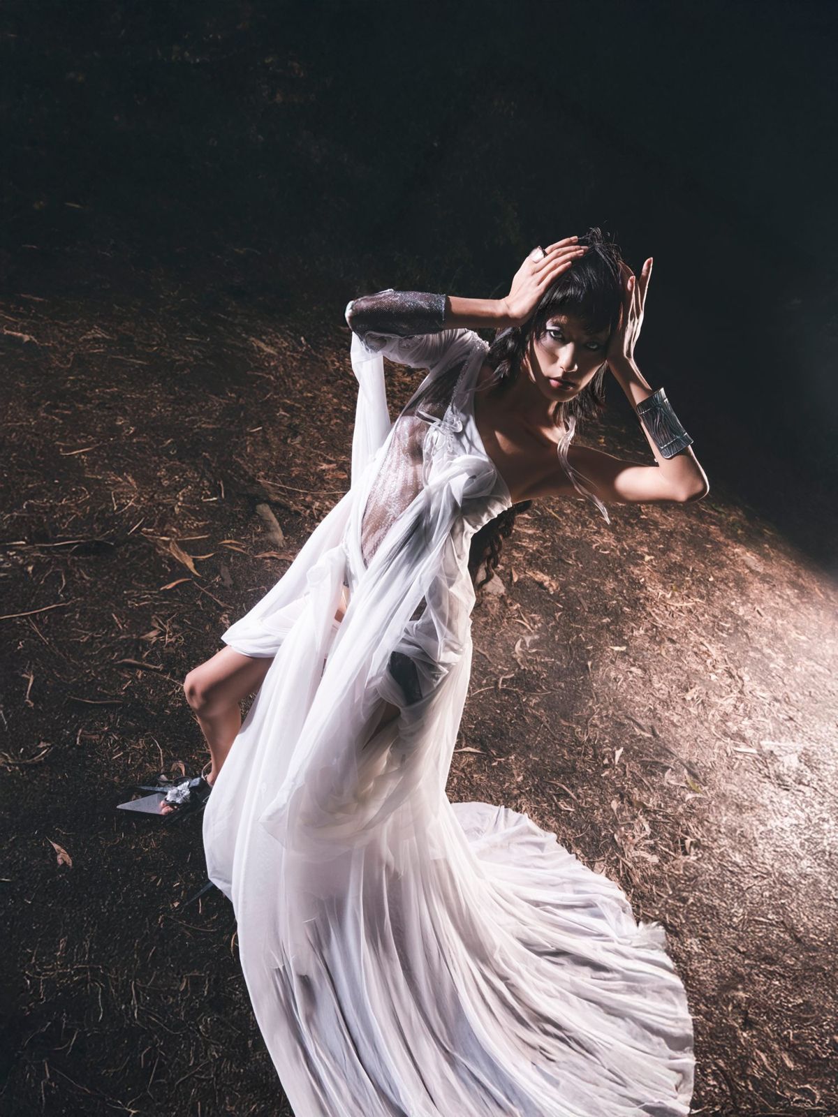 Model reclining on a lit mound in a sheer gown
