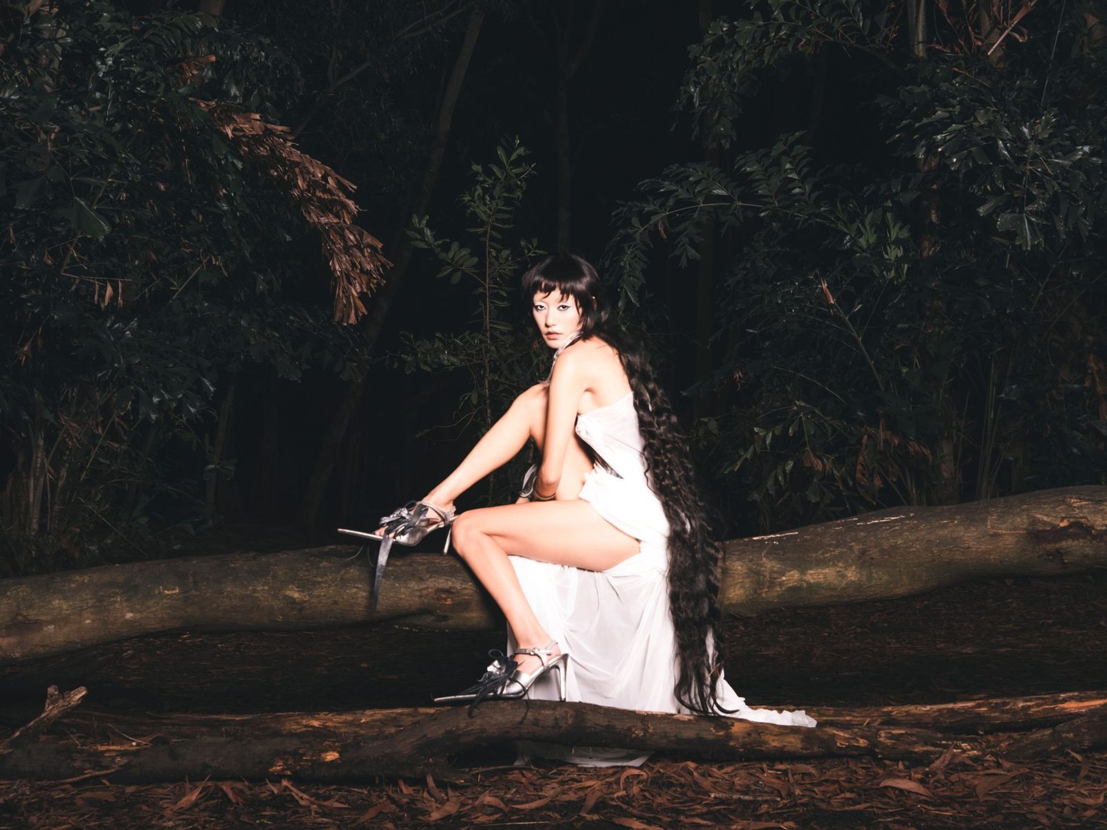 Model seated on a fallen log at night