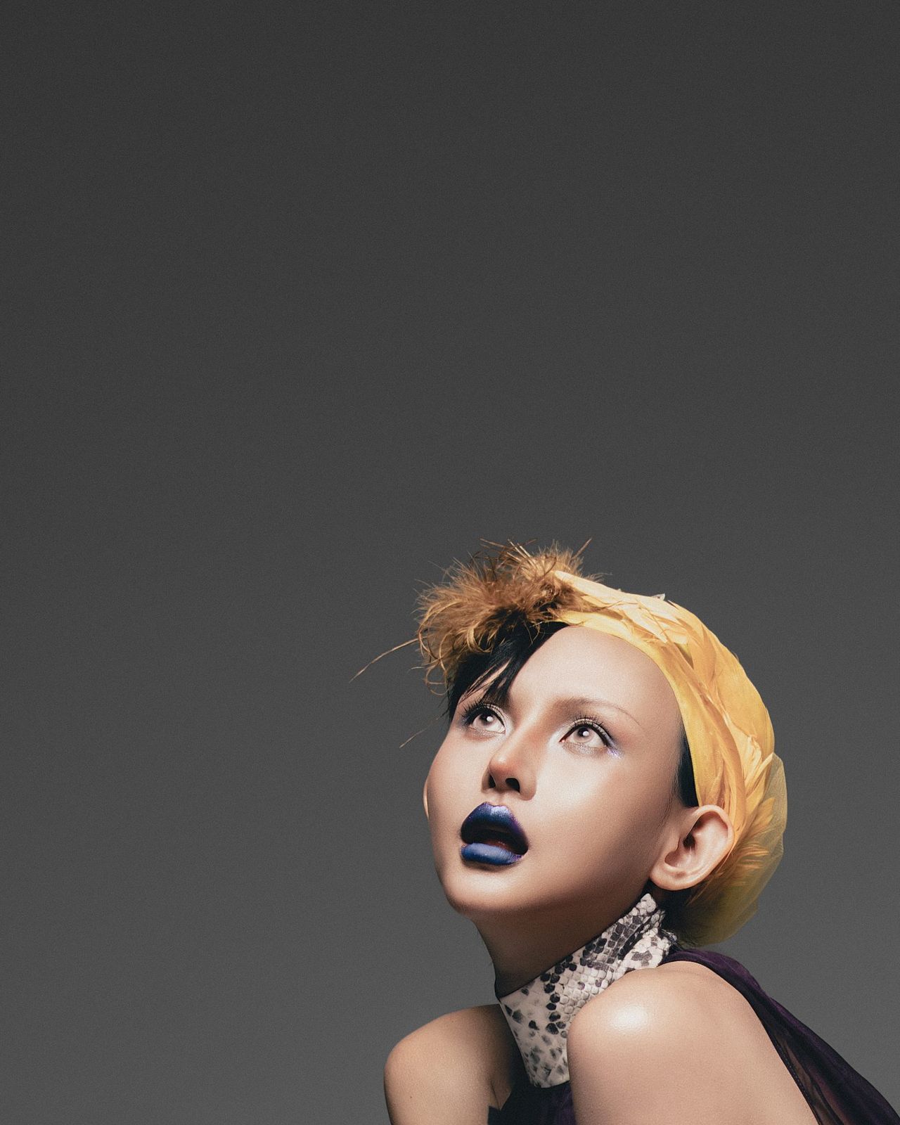 Model gazing upward in a yellow head wrap