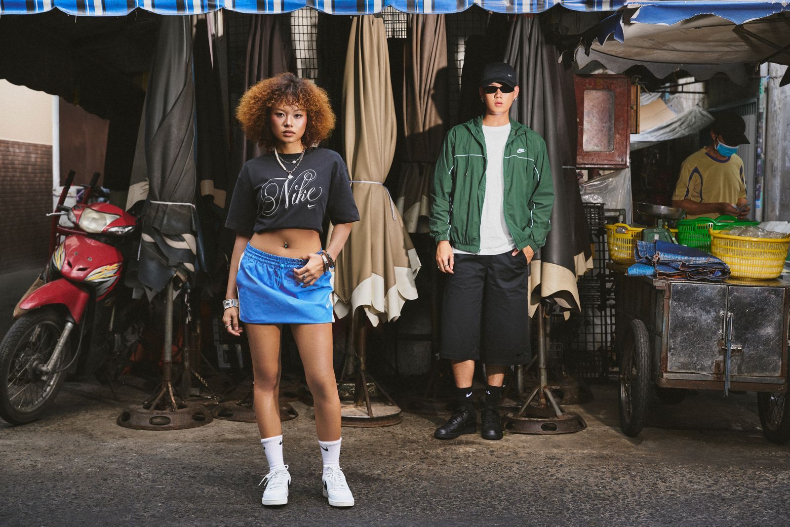 Two models in Nike streetwear outside a market stall
