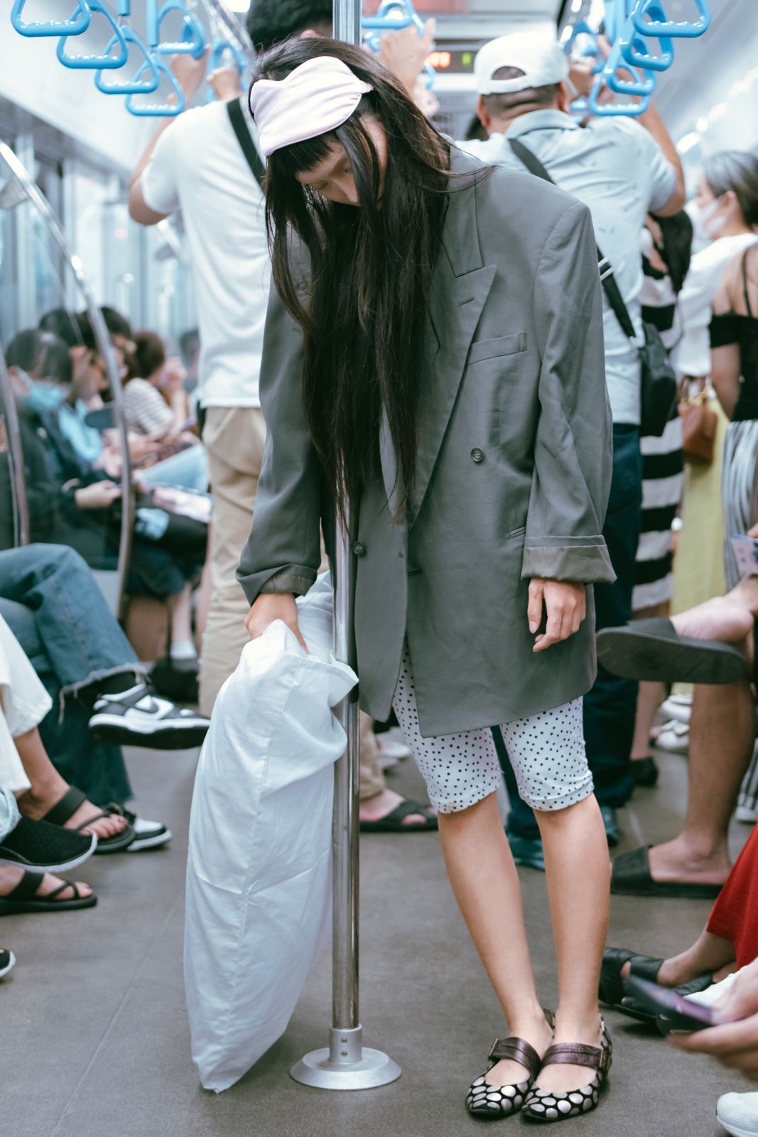A woman asleep on a pillow on a subway train